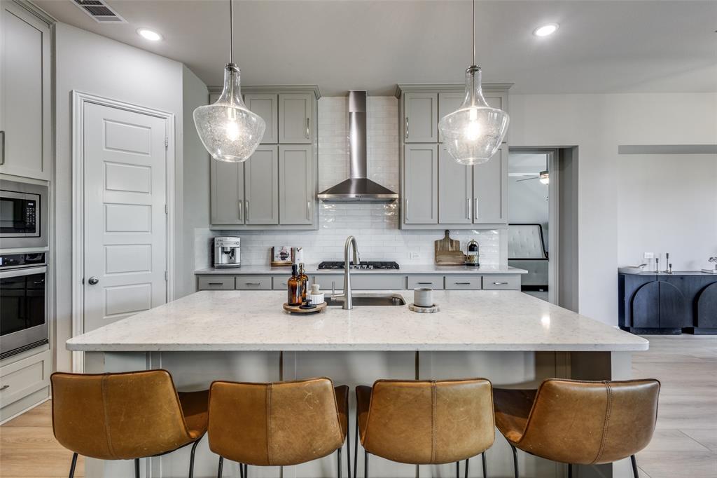 1113 Stone Bridge Pass Gunter, TX 75058 - Photo 12 of 32 a kitchen with granite countertop a table chairs stove and refrigerator