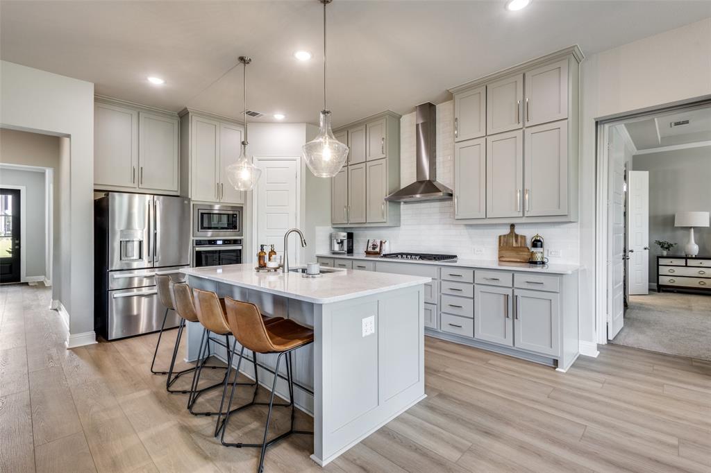 1113 Stone Bridge Pass Gunter, TX 75058 - Photo 8 of 32 a kitchen with stainless steel appliances granite countertop a refrigerator a sink dishwasher a stove and white countertops with wooden floor