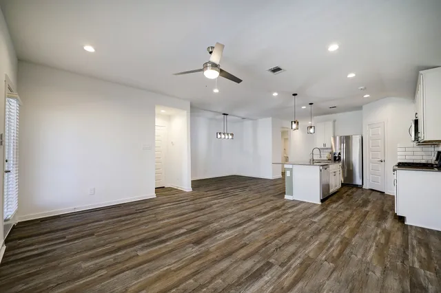 a view of kitchen and empty room with wooden floor