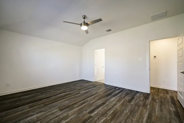 an empty room with wooden floor fan and windows