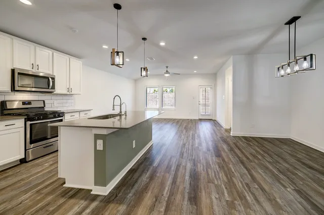 a kitchen with granite countertop wooden floors stainless steel appliances and sink