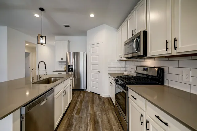 a kitchen with stainless steel appliances granite countertop a sink a stove and a refrigerator