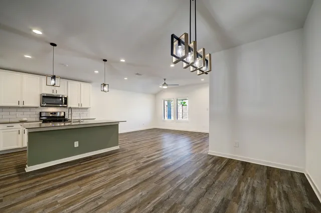 a view of a kitchen with a sink and dishwasher a stove top oven with wooden floor
