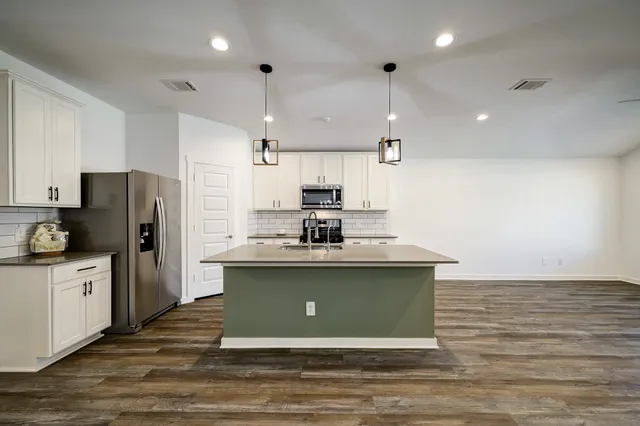 a kitchen with stainless steel appliances granite countertop a sink a stove a refrigerator cabinets and a refrigerator