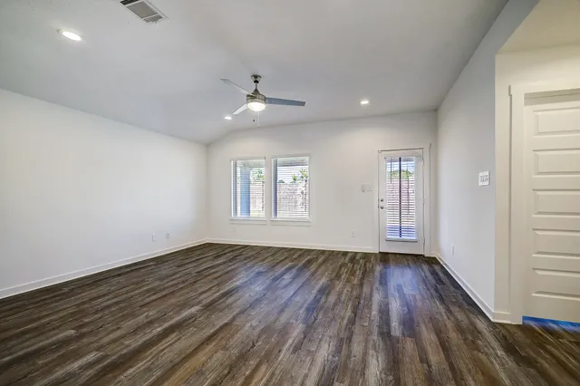 a view of an empty room with wooden floor and a window