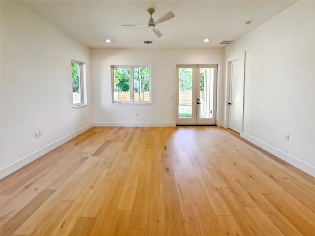 an empty room with wooden floor windows and ceiling fan
