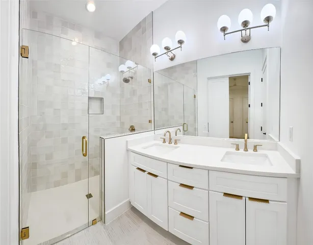 a bathroom with a double vanity sink mirror and shower
