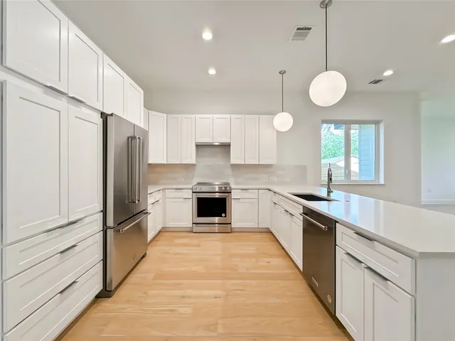 a large kitchen with cabinets a counter and stainless steel appliances