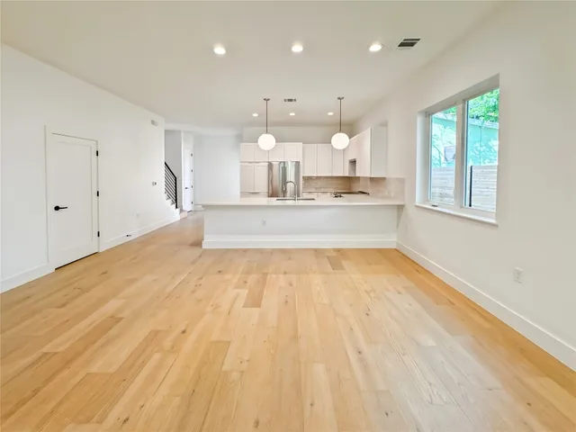 a large kitchen with stainless steel appliances wooden floor and a large window