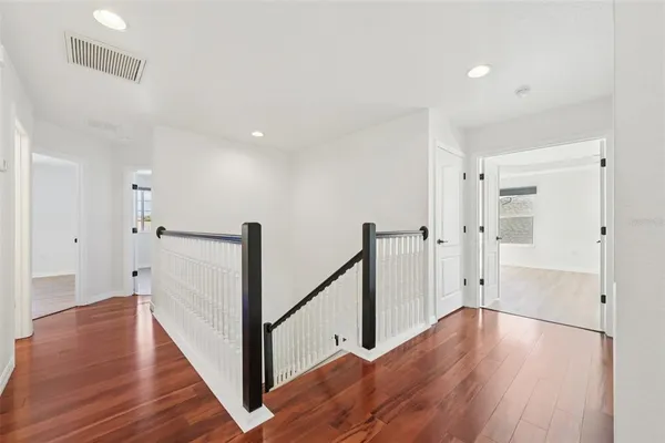 a view of a hallway with wooden floor and staircase