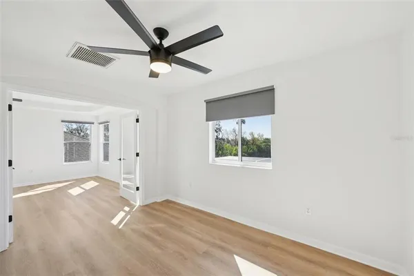 an empty room with wooden floor and windows