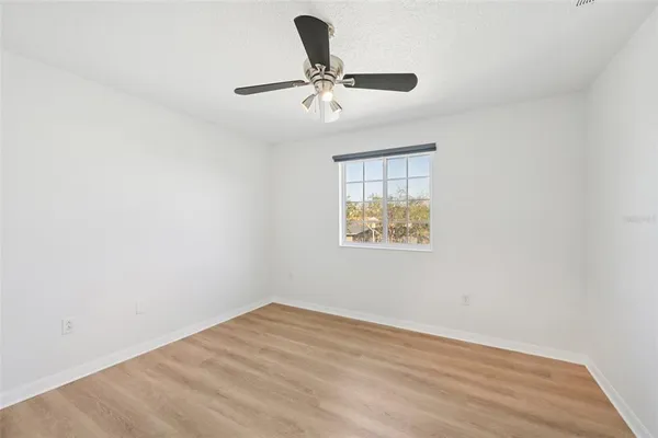 an empty room with a window and a ceiling fan