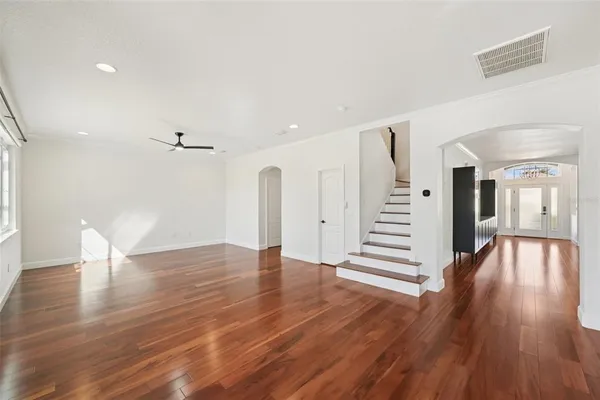 a view of an empty room with wooden floor and stairs