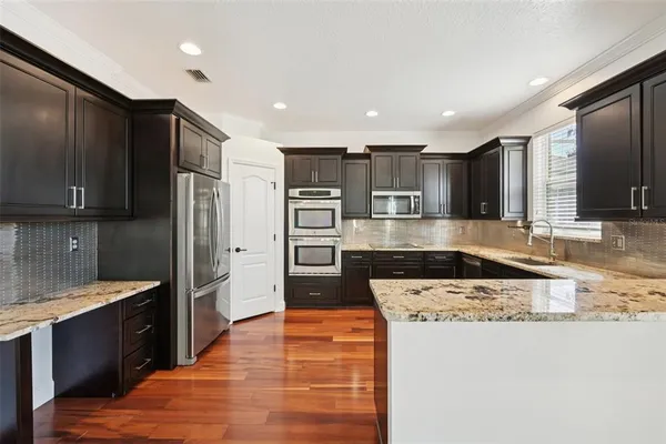 a large kitchen with stainless steel appliances granite countertop a refrigerator and a stove top oven