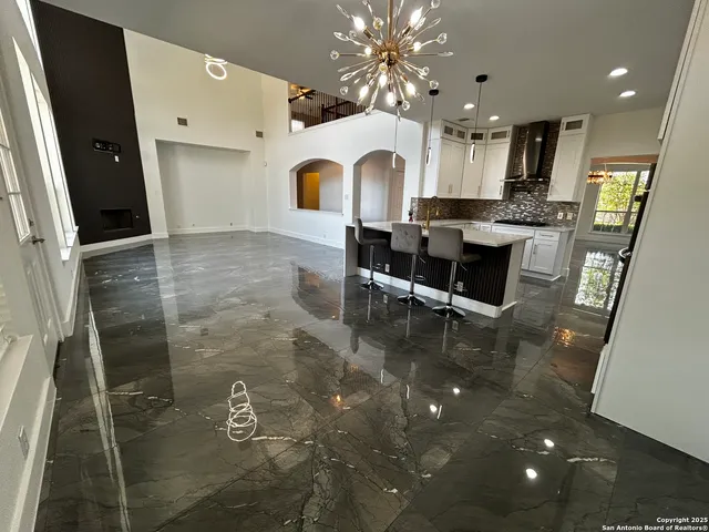 a kitchen with granite countertop a refrigerator a sink a stove a dining table and chairs