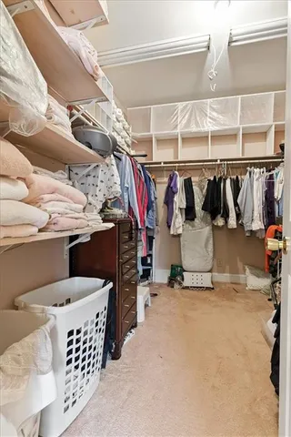 a view of walk in closet with clothes and shoes