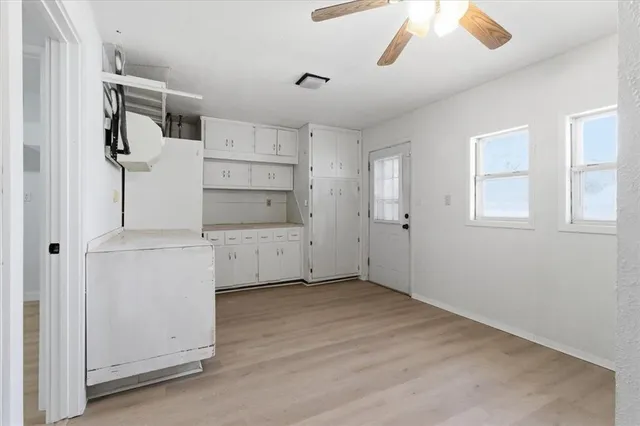 a view of a kitchen with white cabinets and wooden floors