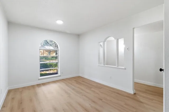 an empty room with wooden floor cabinet and windows