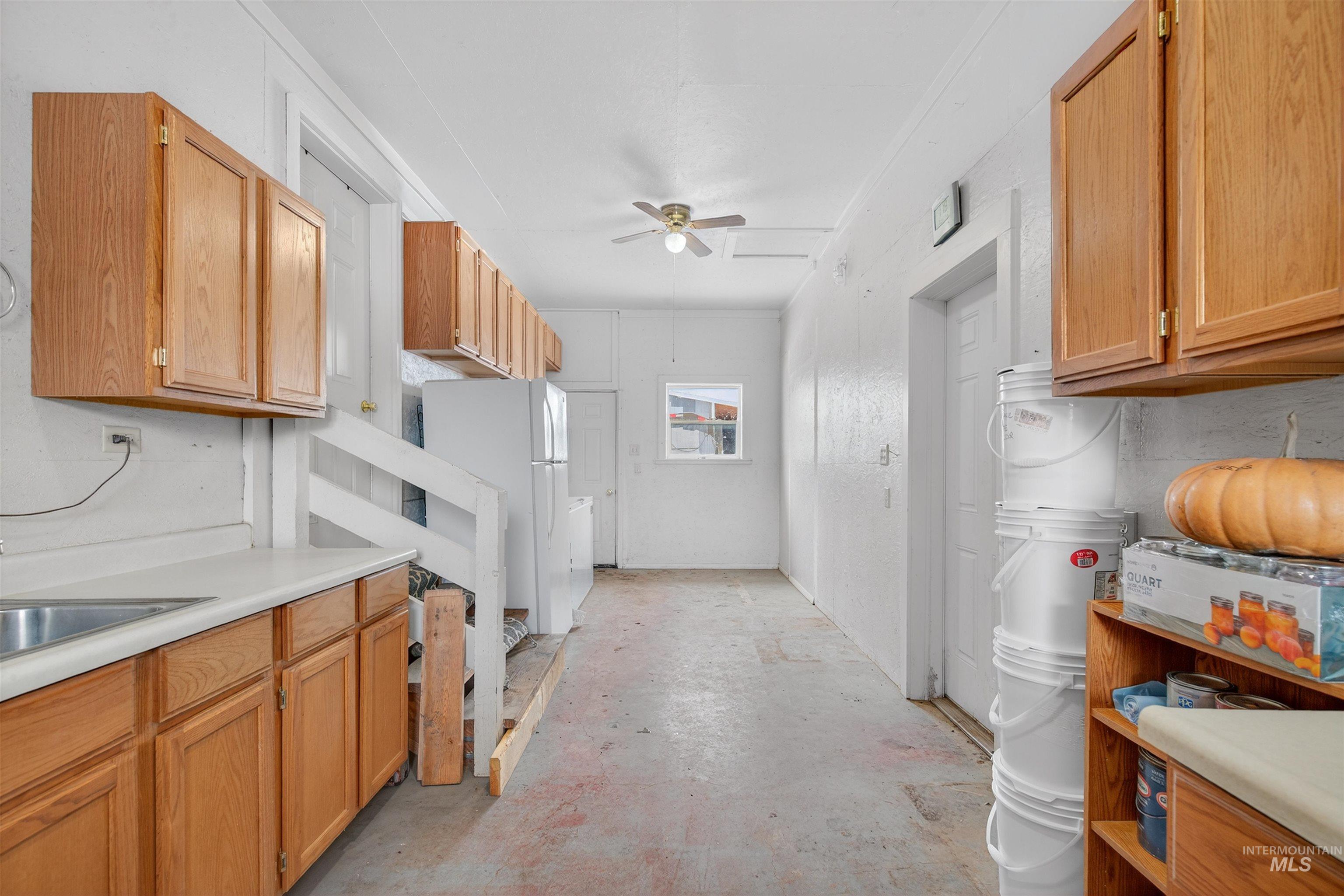 1585 Woodside Road Winchester, ID 83555 - Photo 24 of 47 Kitchen with light countertops, concrete flooring, freestanding refrigerator, ceiling fan, and brown cabinets