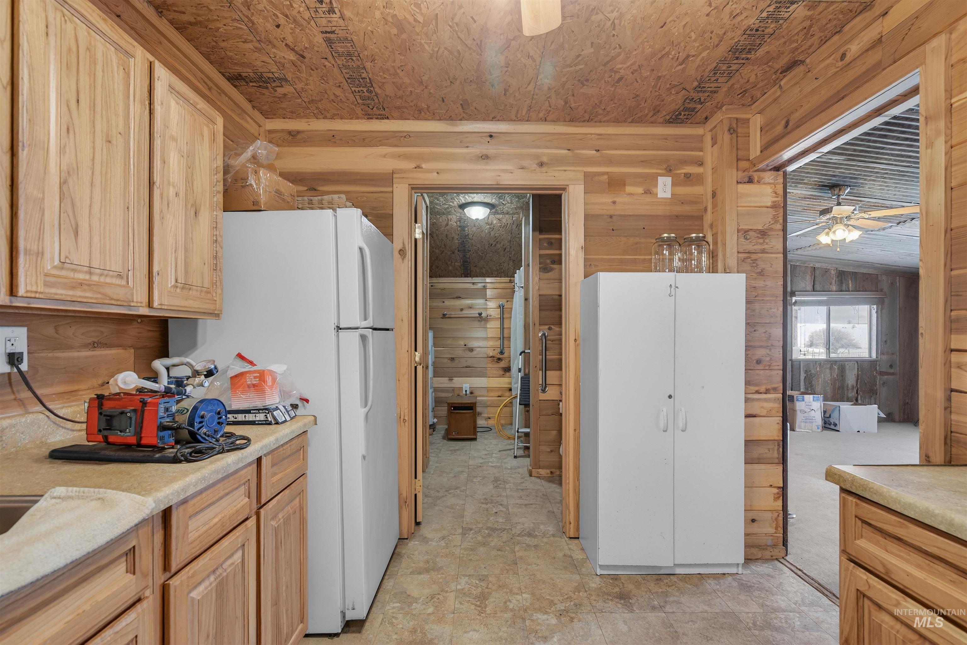 1585 Woodside Road Winchester, ID 83555 - Photo 41 of 47 Kitchen with wooden walls, freestanding refrigerator, light countertops, ceiling fan, and light brown cabinetry