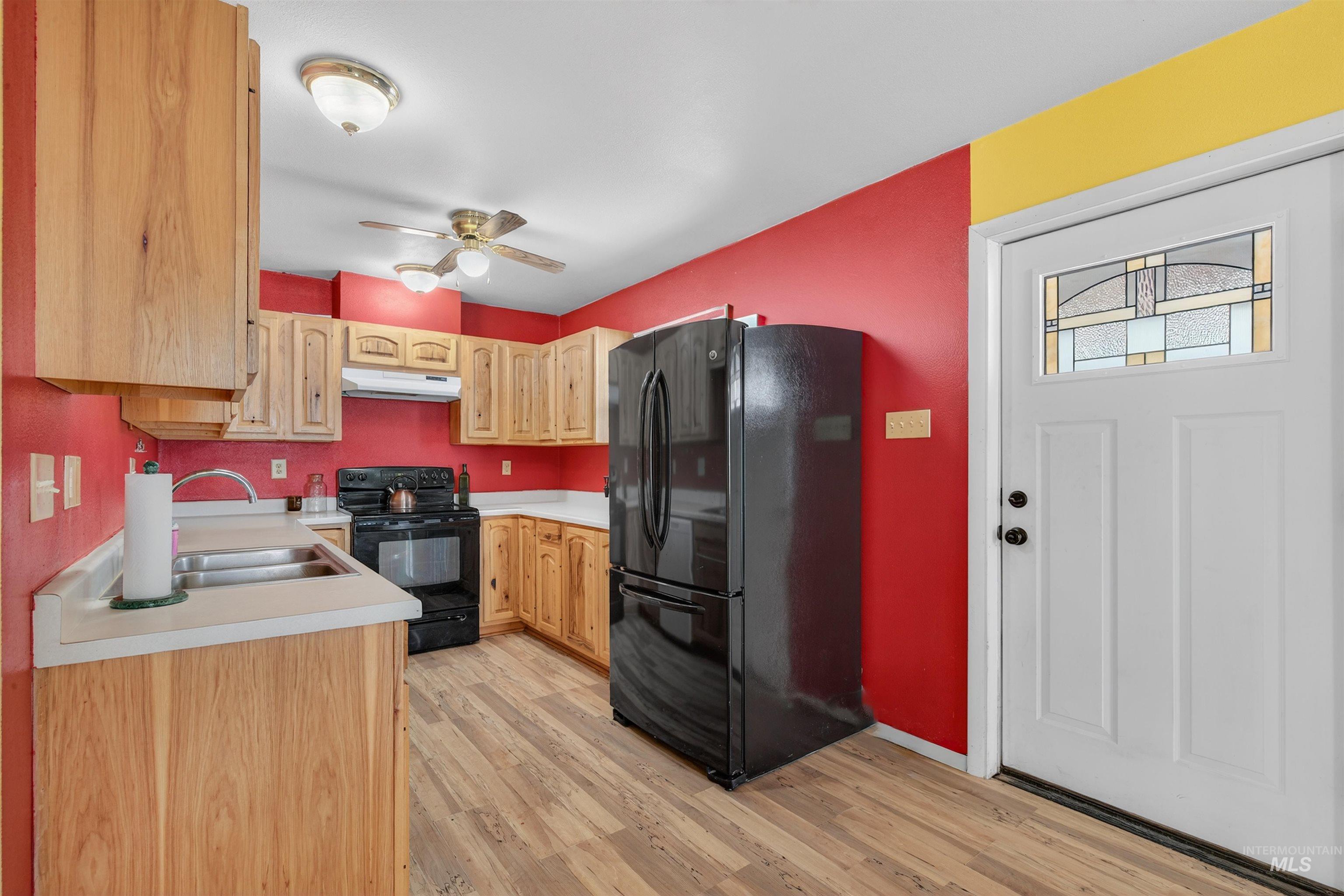 1585 Woodside Road Winchester, ID 83555 - Photo 8 of 47 Kitchen featuring black appliances, light countertops, light brown cabinets, under cabinet range hood, and light wood-type flooring