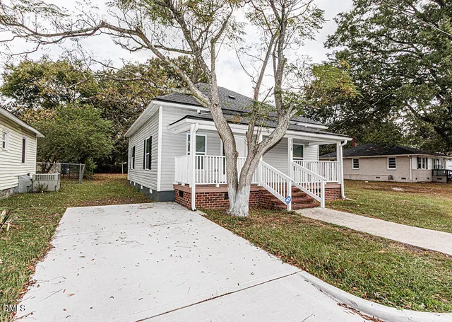 a white house that has a tree in front of it