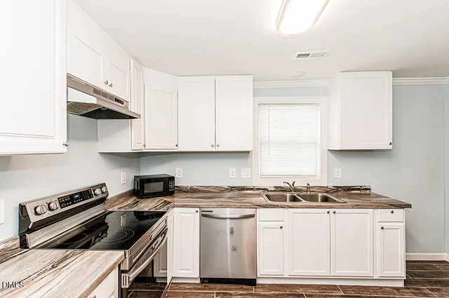 a kitchen with white cabinets and appliances