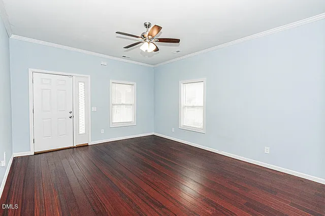 a view of empty room with wooden floor and fan