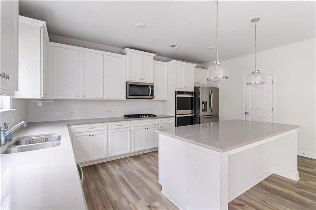 355 Chestnut Chase Hoschton, GA 30548 - Photo 9 of 22 a kitchen with granite countertop a sink a counter top space stainless steel appliances and cabinets