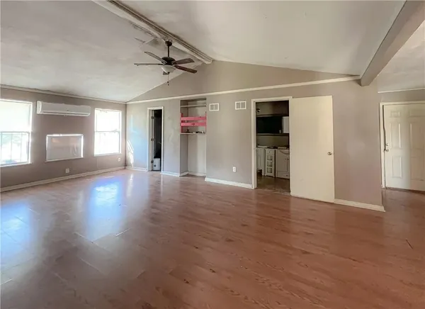 an empty room with wooden floor and windows