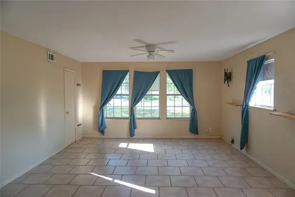 an empty room with windows and fan