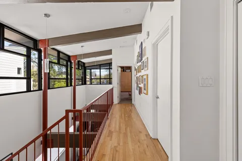 a view of a hallway with wooden floor and stairs