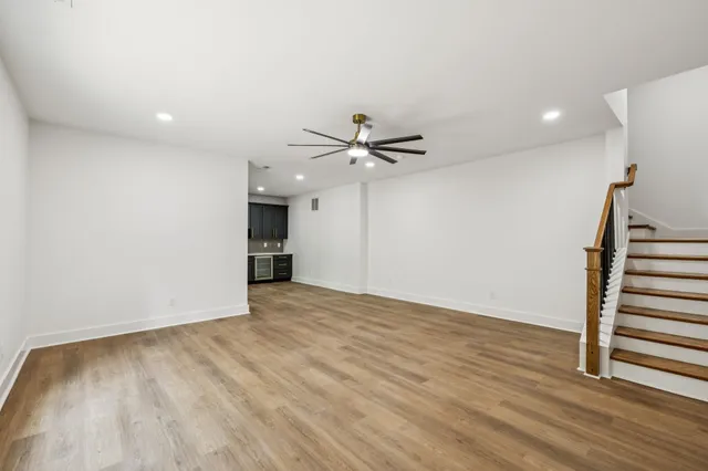 a view of an empty room with wooden floor and a ceiling fan