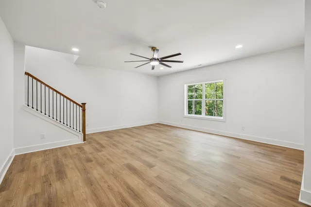 an empty room with wooden floor fan and windows