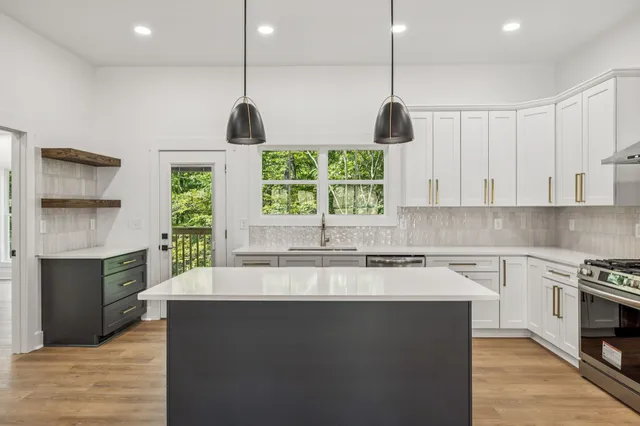 a kitchen with stainless steel appliances granite countertop a stove a sink and a wooden floors