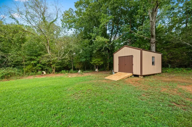 a backyard of a house with plants and large tree