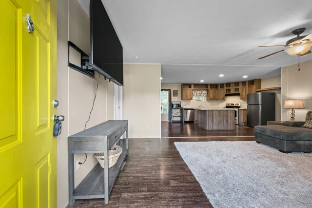 a living room with stainless steel appliances furniture a rug and a kitchen view