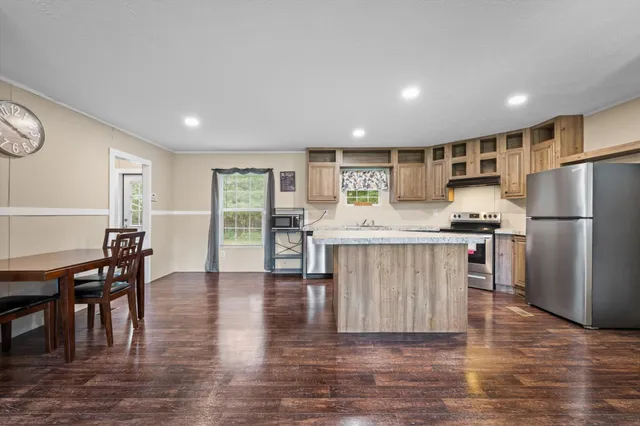a kitchen with stainless steel appliances granite countertop a refrigerator a stove and a dining table with wooden floor