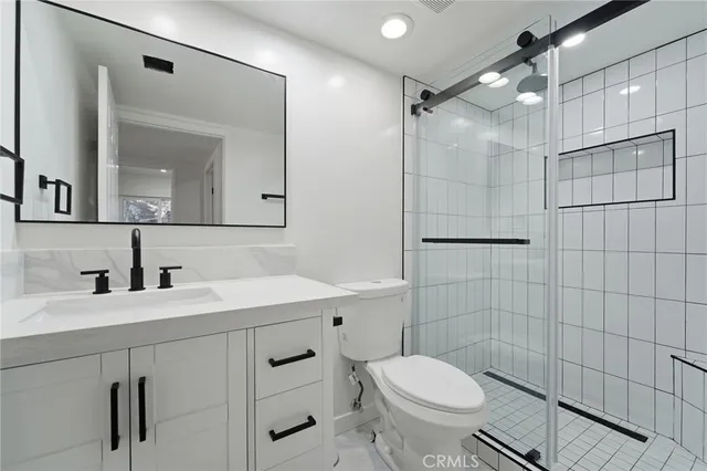 a bathroom with a sink a toilet a mirror and shower