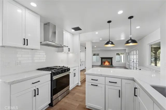 a kitchen with kitchen island a counter space a stove a refrigerator and a sink with wooden floor