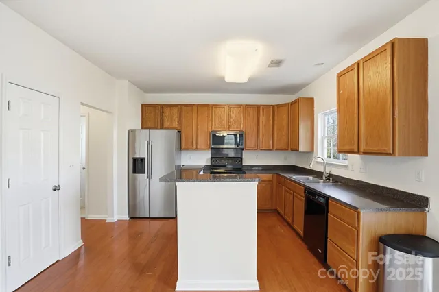 a kitchen with stainless steel appliances granite countertop a refrigerator a sink dishwasher a stove with large countertops and cabinets