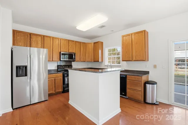 a kitchen with granite countertop a refrigerator stove top oven and sink