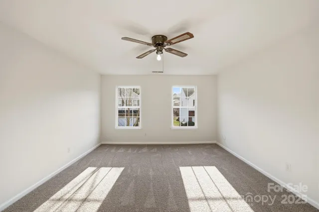 a view of empty room with wooden floor and ceiling fan