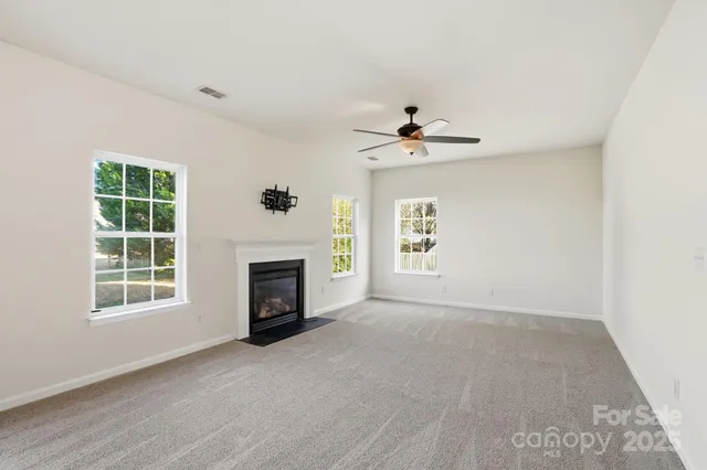 an empty room with windows and fireplace
