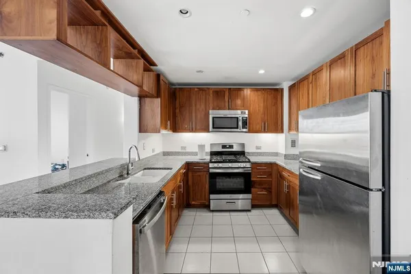 a kitchen with stainless steel appliances granite countertop a stove top oven a sink dishwasher a dining table and chairs with wooden floor