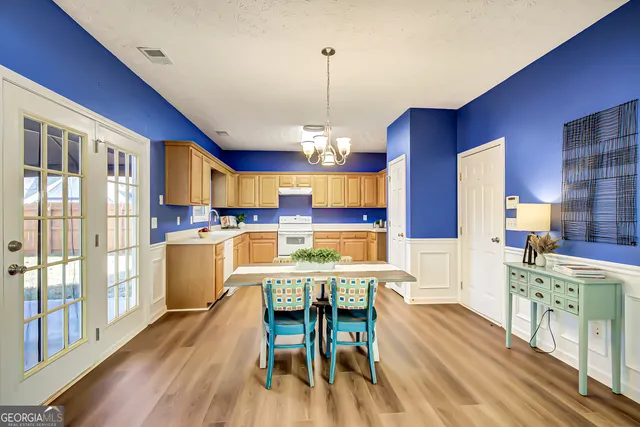 a kitchen with stainless steel appliances granite countertop a stove a refrigerator a kitchen island a dining table and chairs