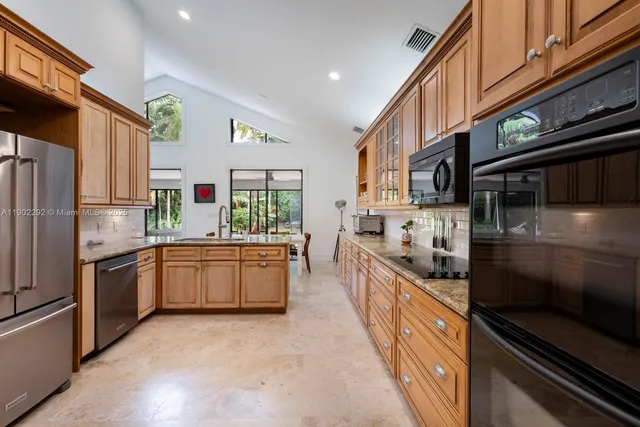 a kitchen with stainless steel appliances granite countertop a refrigerator a stove and a sink