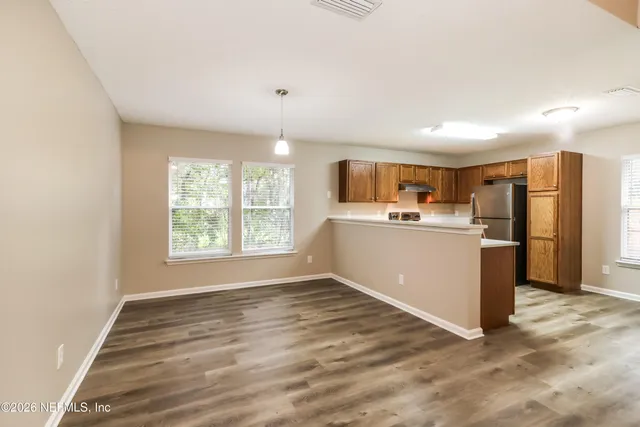 a room with stainless steel appliances kitchen island granite countertop a refrigerator and a sink