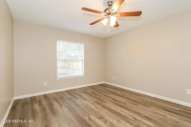 an empty room with a window and a fan