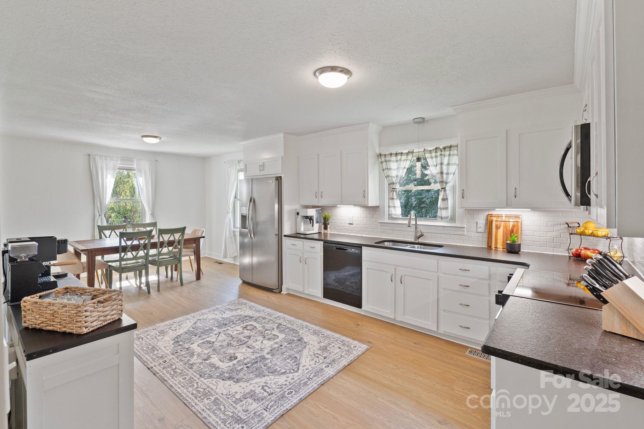 5703 Valley Field Road Southeast Hickory, NC 28602 - Photo 3 of 33 a kitchen with stainless steel appliances granite countertop a stove top oven a sink a dining table and chairs with wooden floor